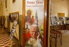 Wnętrze szkoły i wystawy przygotowane z okazji jubileuszu. Na pierwszym planie plansza z podobizną Matki Boskiej i świętego Jana Pawła II