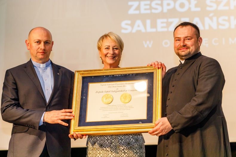 Uroczyste przekazanie nagrody województwa Złotego Medalu Polonia Minor. Iwona Gibas z zarządu województwa oraz księża salezjanie prezentują nagrodę